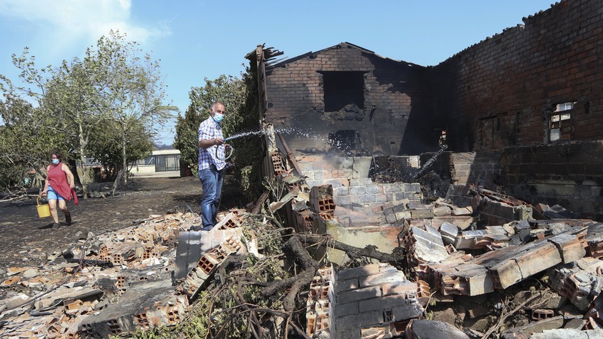 epa10077467 A man tries to put out the flames of his house burned by a fire started in the village of San Martin de Tabara (Zamora), Spain, 18 July 2022. The heat wave sweeping across Spain is fueling ...