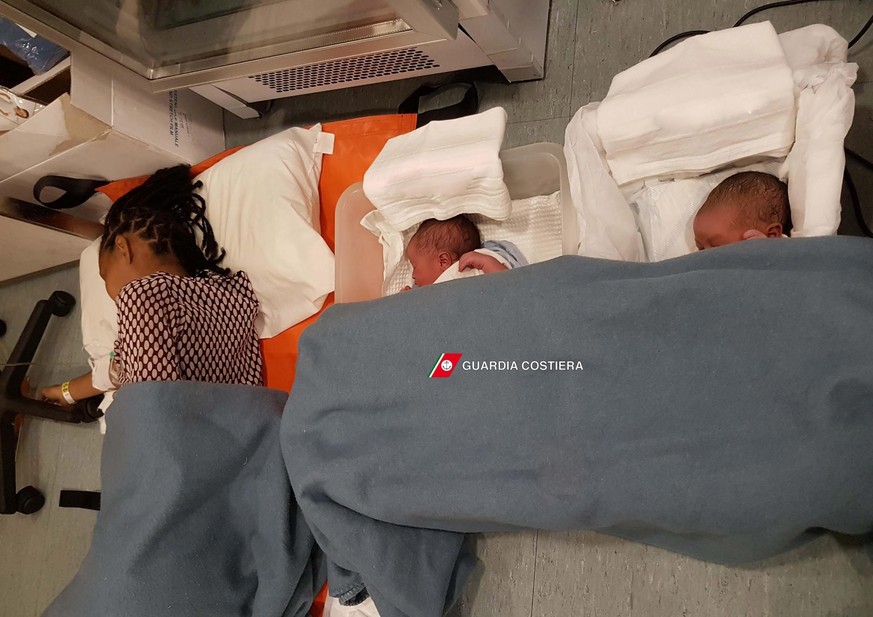 epa05570946 A handout picture provided by Guardia Costiera shows two newborn babies with their mother as they lay on a stretcher after being rescued, on the Guardia Costiera Dattilo ship in the Medite ...