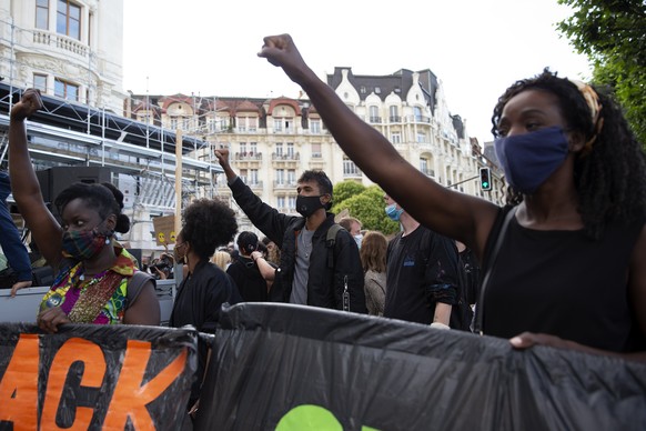 epa08525633 Demonstrators raise their fist as they take part in an anti-racism demonstration, against police violence, during a Black Lives Matter (BLM) protest, in Geneva, Switzerland, 03 July 2020. ...