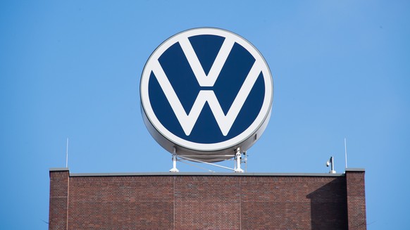 ARCHIV - 11.08.2021, Niedersachsen, Wolfsburg: Das VW-Logo auf fem Markenhochhaus von Volkswagen auf dem Gel