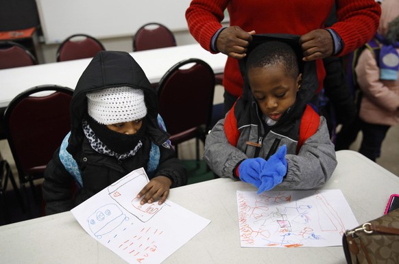 In this Jan. 9, 2018 photo, teacher Loraine Wilson, top right, helps bundle up pre-kindergarten students as they wait to be picked up at the end of a school day at Lakewood Elementary School in Baltim ...