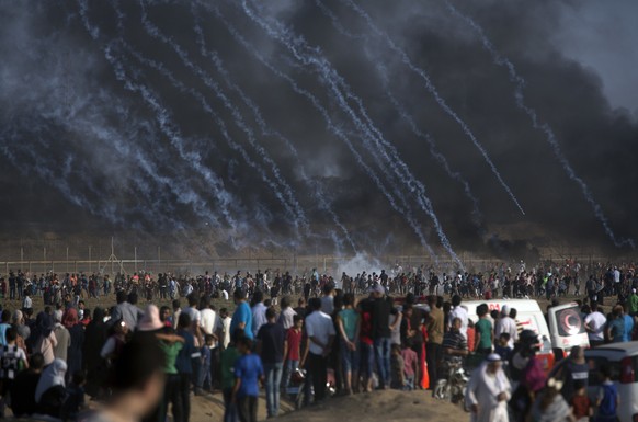 Teargas canisters fired by Israeli troops fall over Palestinians during a protest at the Gaza Strip&#039;s border with Israel, Friday, July 13, 2018. Gaza&#039;s Health Ministry says a 15-year-old Pal ...