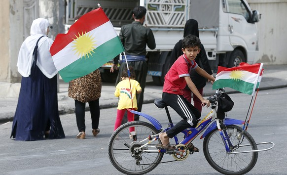 epa06225680 A child rides a bicycle with Kurdistan flags outside a polling station during Kurdistan independence referendum in Erbil, Kurdistan region in northern Iraq, 25 September 2017. The Kurdista ...