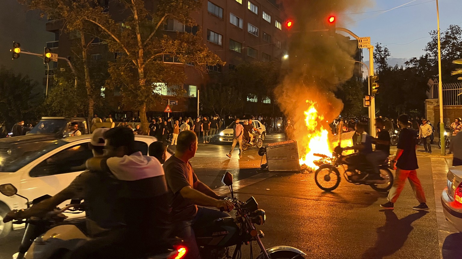 In this Monday, Sept. 19, 2022, photo taken by an individual not employed by the Associated Press and obtained by the AP outside Iran, a police motorcycle and a trash bin are burning during a protest  ...