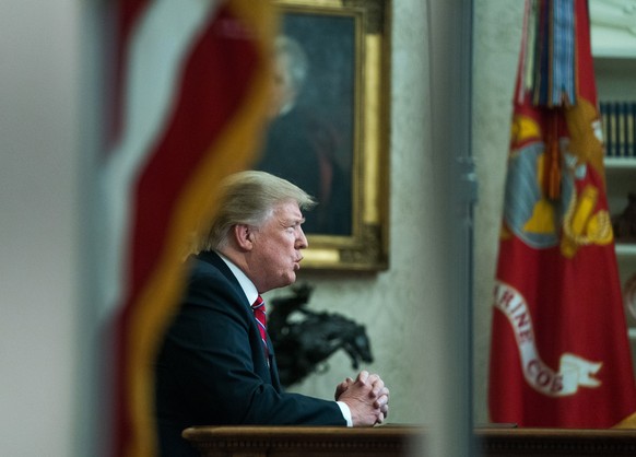 epa07270358 US President Donald J. Trump is seen through a window of the Oval Office as he delivers a televised address to the nation from the Oval Office at the White House in Washington, DC, USA, 08 ...