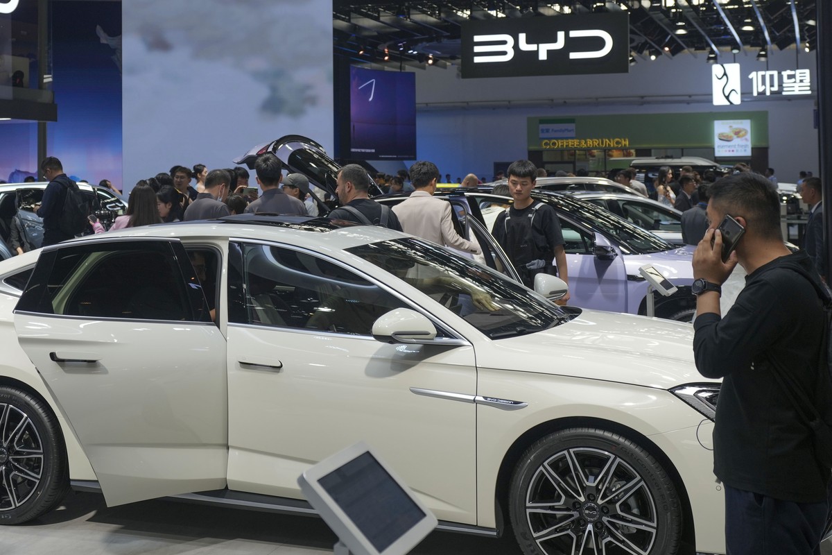 FILE - Visitors look at cars at the BYD booth during the China Auto Show in Beijing, China, Friday, April 26, 2024. The European Union threatened on Wednesday, june 12, 2024, to hike tariffs on Chines ...