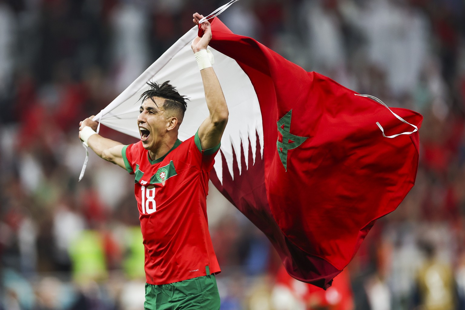 epa10359738 Jawad El Yamiq of Marrocco waves the Qatar and the Morocco flags as he celebrates after the FIFA World Cup 2022 quarter final soccer match between Morocco and Portugal at Al Thumama Stadiu ...