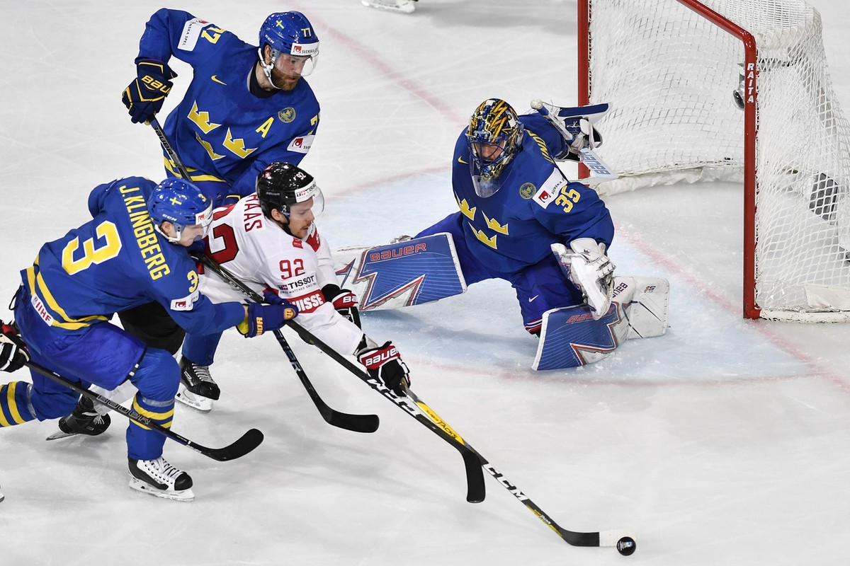 Switzerland's Gaeetan Haas, center, in action against Sweden's Victor Hedmann, left, and goaltender Henrik Lundqvist during their Ice Hockey World Championship quarter final match between Sw ...