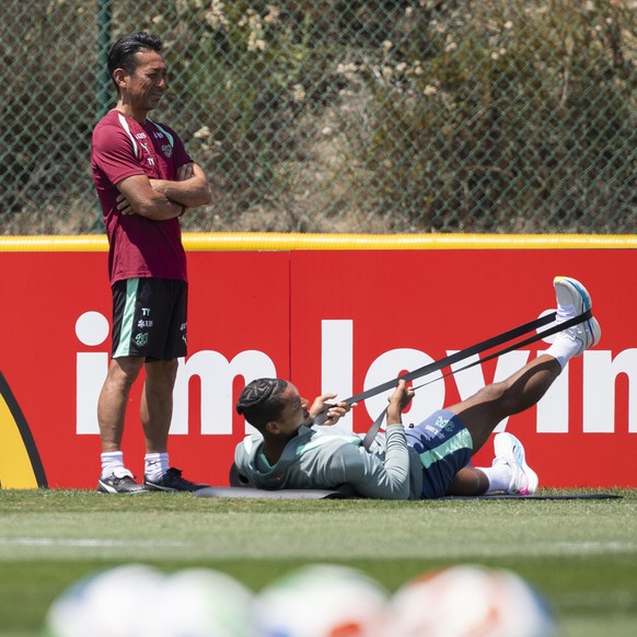 Switzerland's Granit Xhaka, left, and Manuel Akanji exercise stretching next to physio therapist Takahiro Yamamoto during a training session of the Swiss national soccer team at the SDJA in San D ...