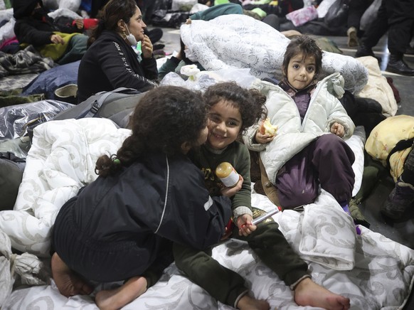 Migrants settle for the night in the logistics center in the checkpoint &quot;Kuznitsa&quot; at the Belarus-Poland border near Grodno, Belarus, on Thursday, Nov. 18, 2021. A plane carrying migrants ba ...