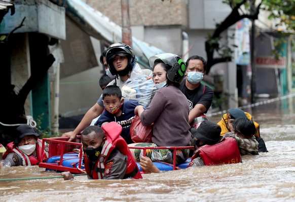 epa09619070 Indonesian national police wade through flood water as they rescue residents in Jakarta, Indonesia, 20 February 2021. At least 21 areas flooded following heavy rains, during which thousand ...