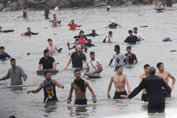 epa13143412 A group of migrants remains on the beach near the Tarajal border crossing in Ceuta, Spain, 31 July 2026. Violent clashes occurred along the border perimeter as migrants attempted to enter  ...