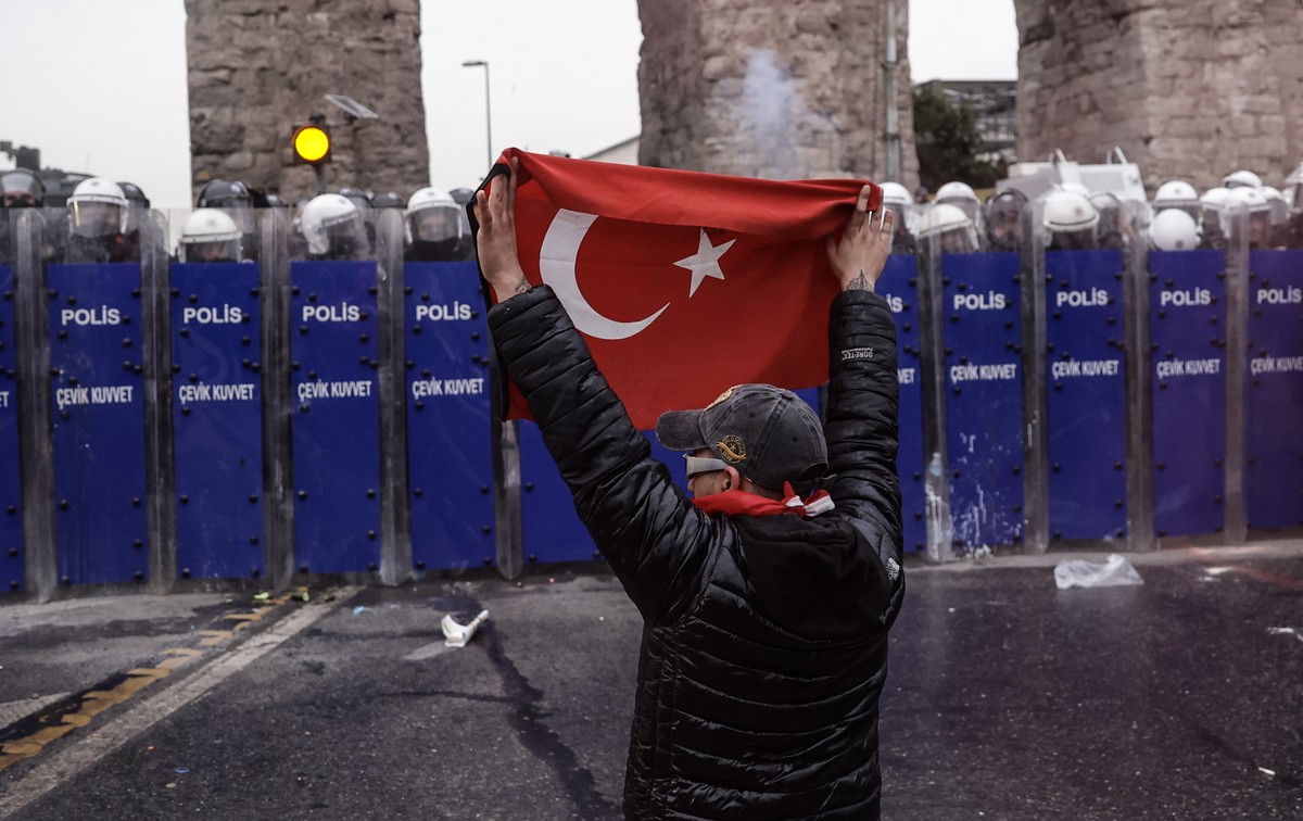 epa11984020 A masked protester confronts Turkish riot police as demonstrators try to march to Taksim Square from the Istanbul Municipality headquarters during a protest against the detention of Istanb ...