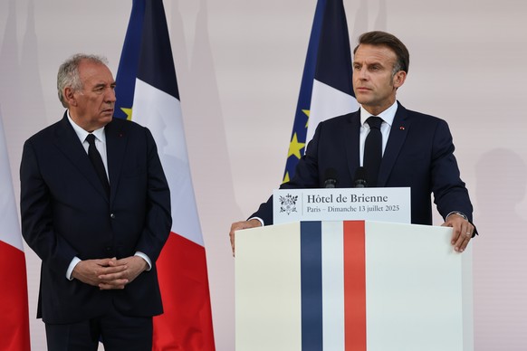 epa12236073 France Prime Minister Francois Bayrou (L) looks on as French President Emmanuel Macron (R) delivers a speech to army leaders on the eve of the annual Bastille Day Parade, at the l?Hotel de ...