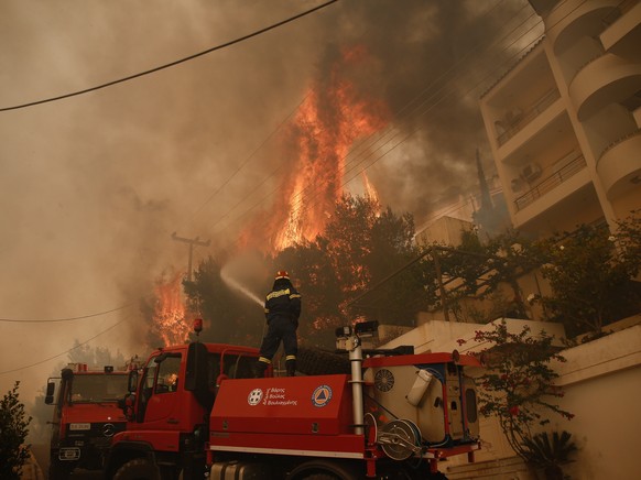 epa09995949 A fireman tries to extinguish flames during a wildfire in the suburb of Voula, south of Athens, Greece, 04 June 2022. Greek authorities ordered a limited evacuation in the coastal suburb o ...