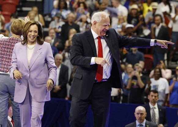 epa11544432 Democratic presidential candidate, Vice President Kamala Harris (L) and Democratic vice presidential candidate Minnesota Governor Tim Walz acknowledge the crowd during a rally at the Unive ...