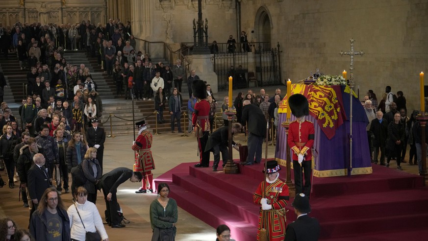 Members of the public file past the coffin of Queen Elizabeth II, draped in the Royal Standard with the Imperial State Crown and the Sovereign's orb and sceptre, lying in state on the catafalque ...