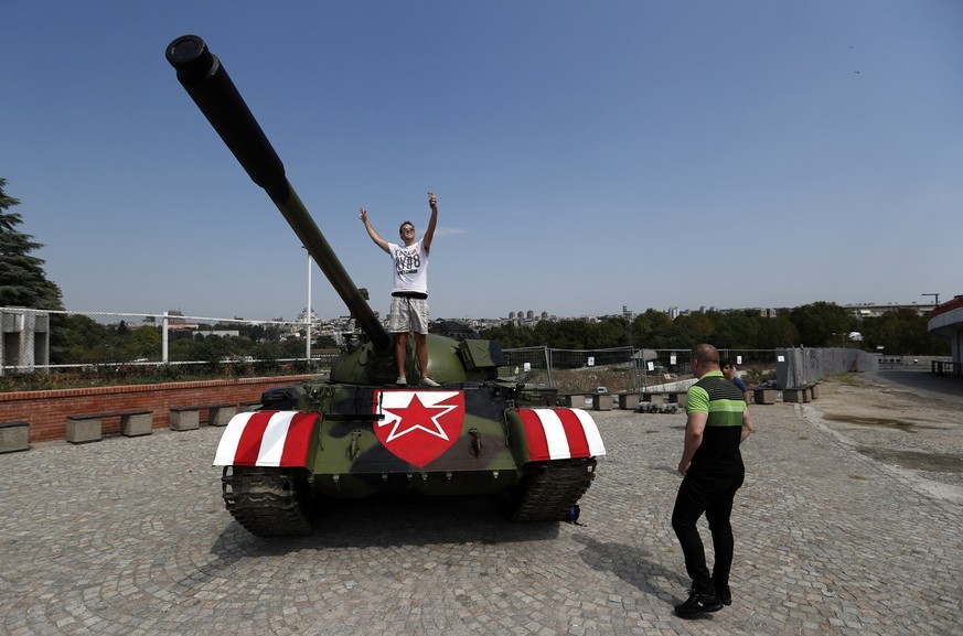 People pose with a former Yugoslav army T-55 battle tank seen in front of northern grandstand of Rajko Mitic stadium in Belgrade, Serbia, Tuesday, Aug. 27, 2019, placed as a gesture of support for the ...