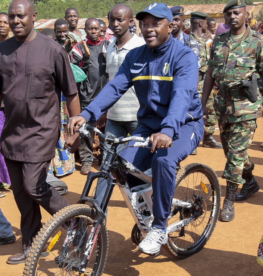 President Pierre Nkurunziza arrives riding a bicycle, accompanied by First Lady Denise Bucumi Nkurunziza, right, to cast his vote for the presidential election, in Ngozi, Burundi Tuesday, July 21, 201 ...
