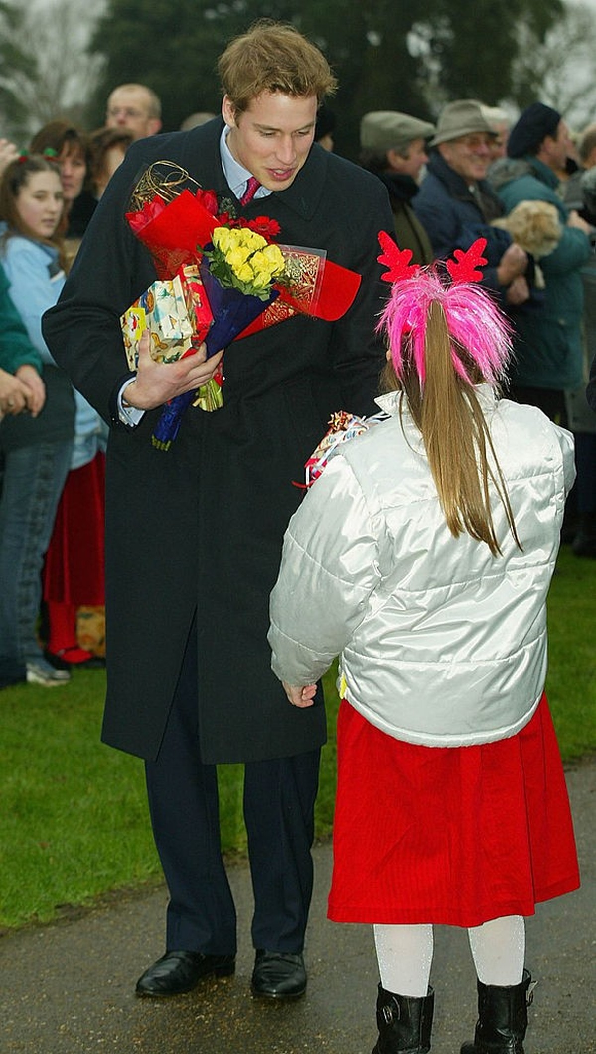 SANDRINGHAM, UNITED KINGDOM - DECEMBER 25: Britain's Prince William receives a gift from a young girl after members of the British Royal family attended a Christmas Day service at Sandringham Chu ...
