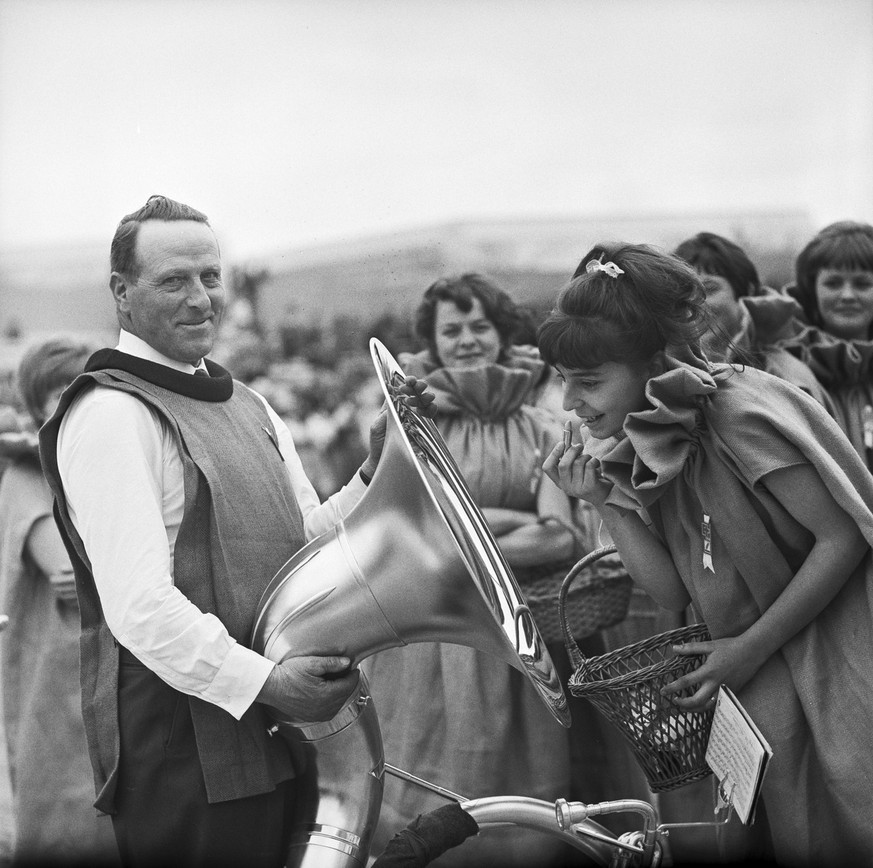 Eine Frau schminkt sich die Lippen mit einer Tuba als Spiegel am Bauerntag der Landesaustellung Expo 64 in Lausanne, aufgenommen im Jahr 1964. (KEYSTONE/Str)