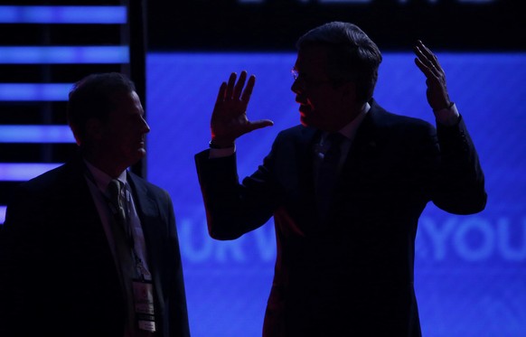 Republican presidential candidate and former Governor Jeb Bush (R) talks to another man at the edge of the debate stage during a break in the Republican U.S. presidential candidates debate sponsored b ...