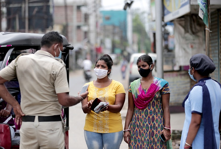 epa08591227 Police officers stop the commuters at a newly added containment zone near Kolkata, eastern India, 08 August 2020. Bengal government announced a complete lockdown for two days in a week. In ...