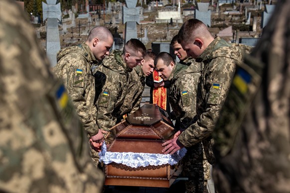 epaselect epa09840619 Soldiers carry the coffin of a comrade during the funeral ceremony at the Lyczakowski cemetery in Lviv, Ukraine, 21 March 2022. On 24 February Russian troops had entered Ukrainia ...