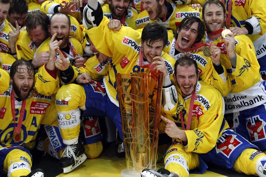 Die HC Davos Spieler Beat Forster, links, Robin Grossmann, Mitte, Marc Wieser, Mitte rechts, Mathias Joggi, rechts unten, Yanick Steinmann, oben rechts, und ihre Kollegen posieren mit dem Pokal nach d ...