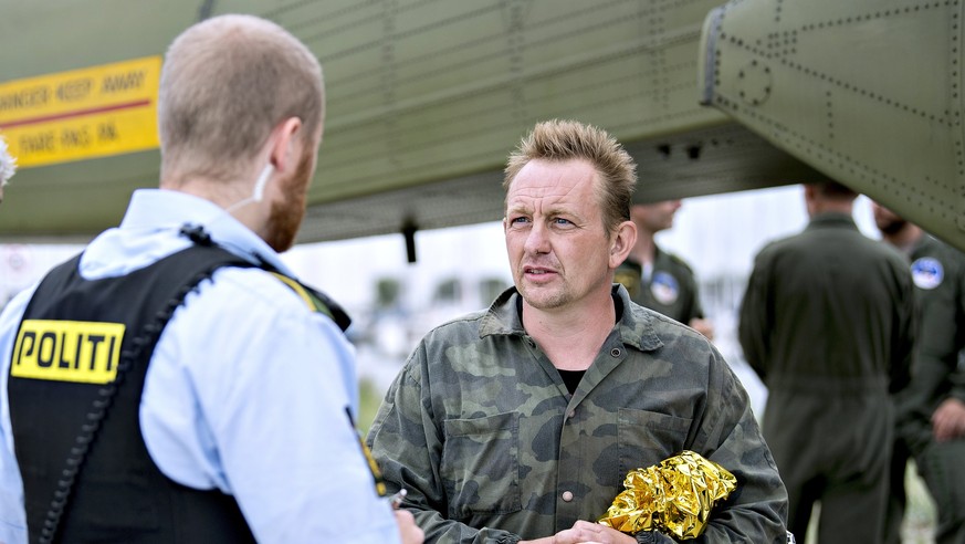 epa06137906 Danish submarine owner and inventor Peter Madsen (R) speaks to a Danish policeman after landing with the help of the Danish defense in Dragor Harbor south of Copenhagen, Denmark, 11 August ...