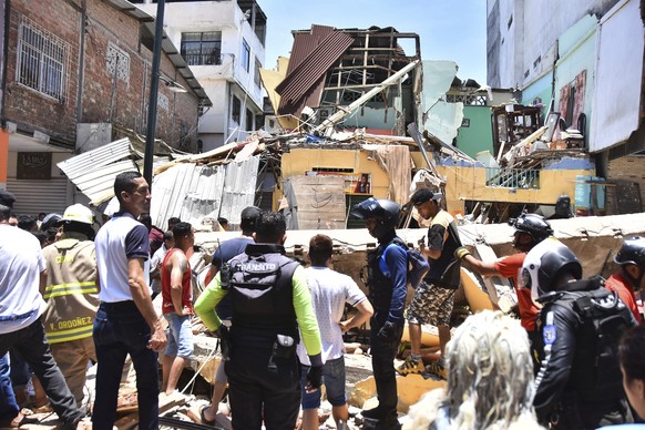 Residents and rescue workers stand in front of buildings brought down by an earthquake that shook Machala, Ecuador, Saturday, March 18, 2023. The U.S. Geological Survey reported an earthquake with a m ...