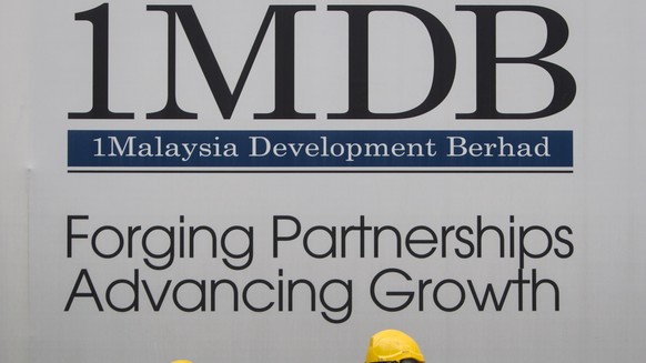 FILE - Construction workers chat in front of a billboard for state investment fund 1 Malaysia Development Berhad (1MDB) at the fund&#039;s flagship Tun Razak Exchange development in Kuala Lumpur, Mala ...