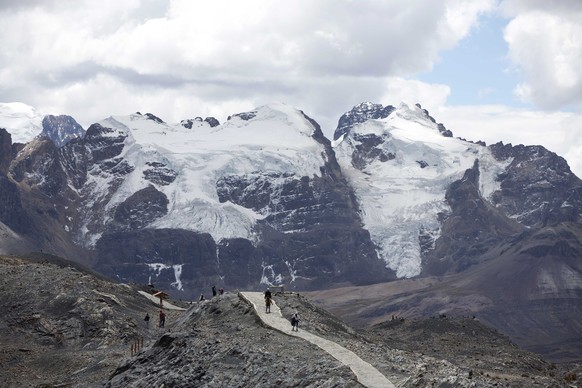 FILE - Tourists walk in front of the Tuco Glacier in Huascaran National Park during a tour called the "Route of climate change" in Huaraz, Peru, August 12, 2016. The South American country has…