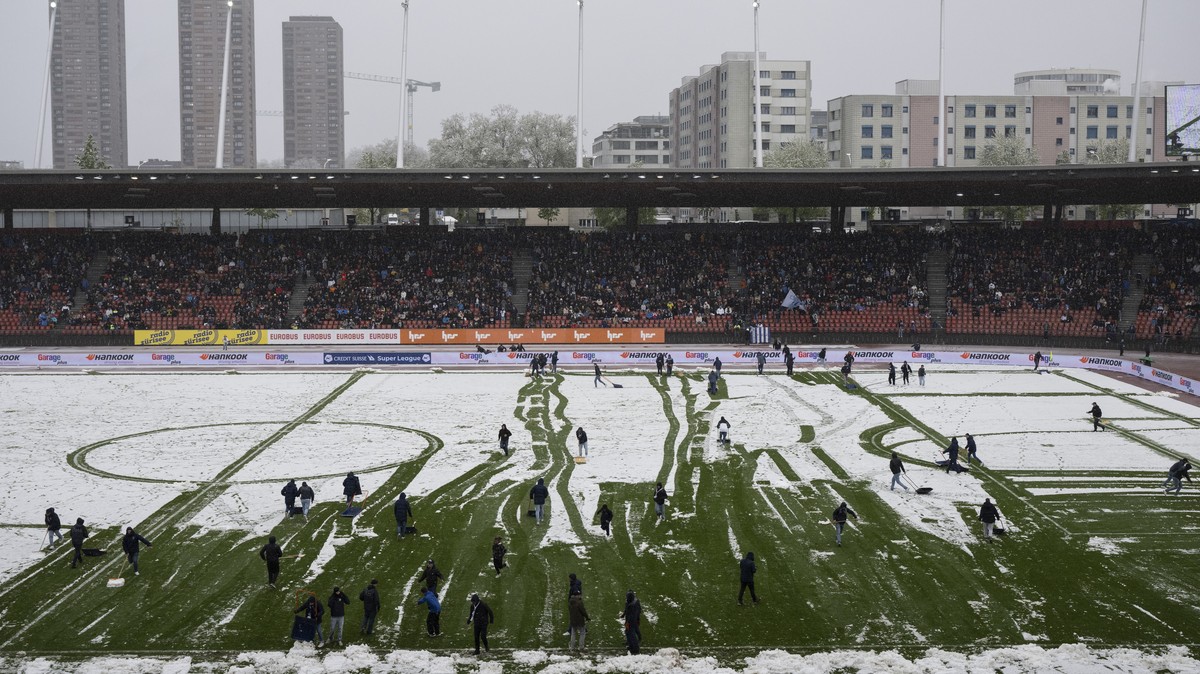 Zuercher Fans helfen bei der Schneeraeumung im Fussball Meisterschaftsspiel der Super League zwischen dem FC Zuerich und dem FC St. Gallen im Letzigrund, am Sonntag, 21. April 2024 in Zuerich. (KEYSTO ...