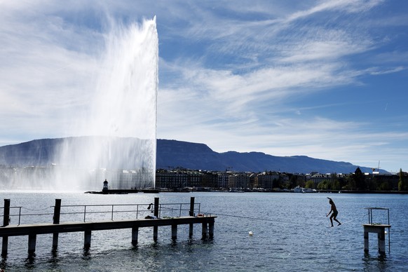 epaselect epa11262148 A man walking a slackline on a warm Spring day at Lake Geneva in front of the Geneva water fountain (Jet d&#039;eau de Geneve) at the &quot;Bains des Paquis&quot; in Geneva, Swit ...