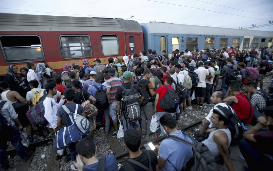 Migrants wait to board a train that would take them towards Serbia, at the railway station in the southern Macedonian town of Gevgelija, on Wednesday, Aug. 12, 2015. Macedonia is facing an increasing  ...