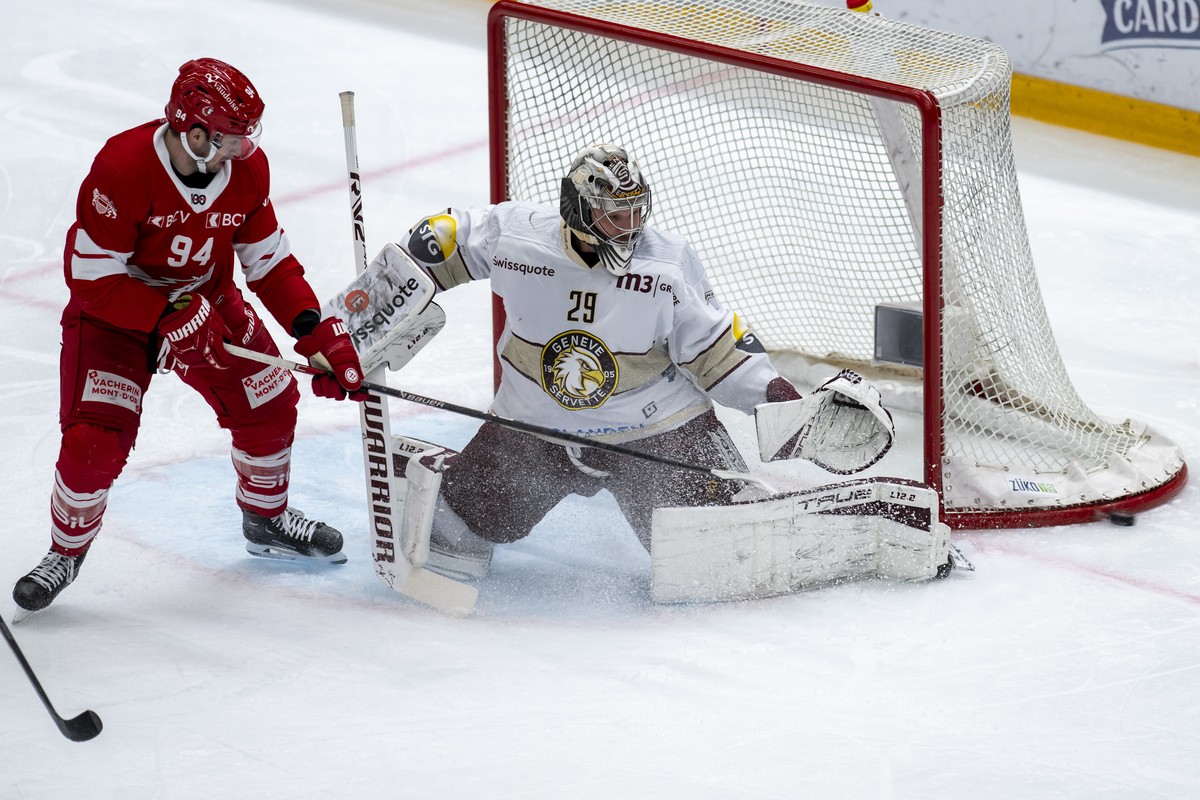 L'attaquant lausannois Tim Bozon, gauche, a la lutte pour le puck avec le gardien genevois Robert Mayer, droite, lors du match du championnat suisse de hockey sur glace de National League LNA, en ...