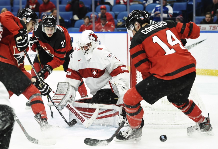 Switzerland&#039;s Matteo Ritz (1) makes a save as Canada&#039;s Alex Formenton, left to right, Brett Howden (21) and Maxime Comtois (14) look for a rebound during the third period of a quarterfinal i ...