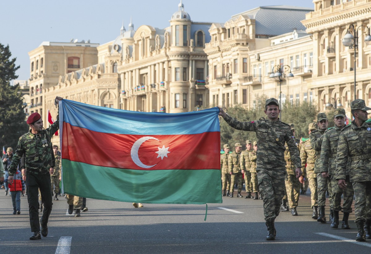 epa09571059 Azeri soldiers carry a national flag on the anniversary of the end of the 2020 war over the Nagorno-Karabakh region between Azerbaijan and Armenia, in downtown Baku, Azerbaijan, 08 Novembe ...
