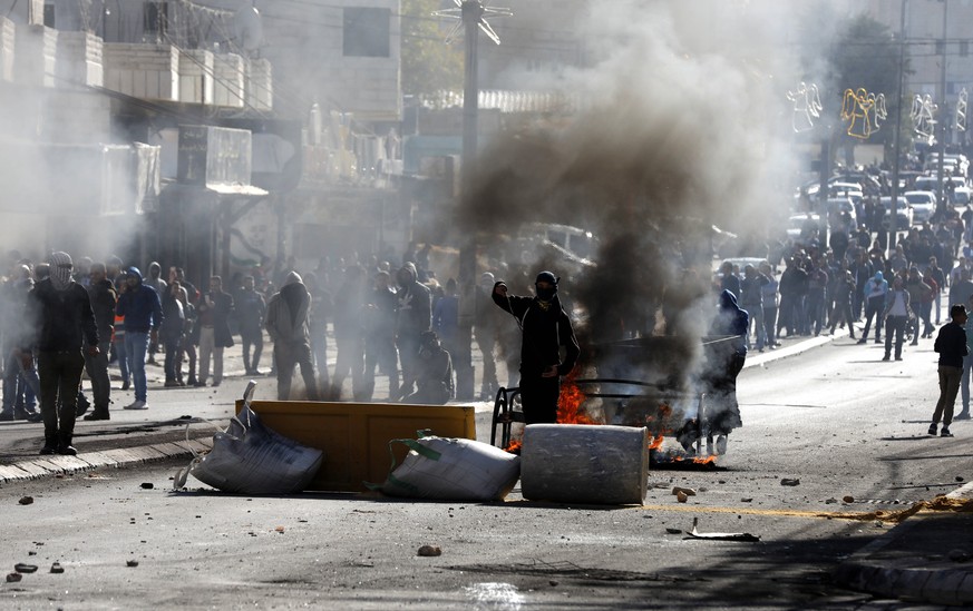 epa06376728 Palestinians throws stones at Israeli troops during clashes in the West Bank City of Bethlehem, 08 December 2017. Palestinians announced general strike and a rage day to protest against US ...