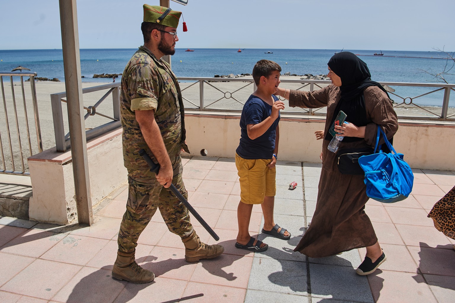A woman speaks with a 12-year-old unaccompanied migrant as a Spanish soldier escorts the child to the Spain-Morocco border from the Spanish enclave of Ceuta, Monday, Aug. 3, 2026. The forced deportati ...