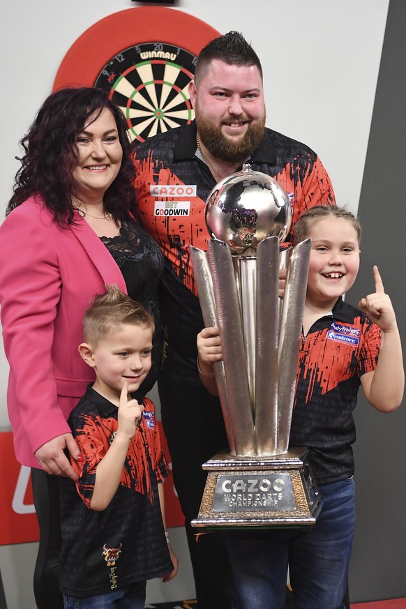 epa10387897 Michael Smith of England and his family pose with the Sid Waddell trophy after winning the PDC World Darts Championship final against Michael van Gerwen of the Netherlands at Alexandra Pal ...