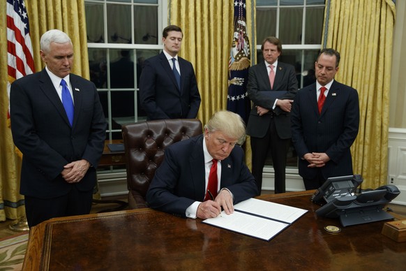 FILE - In this Jan. 20, 2017, file photo,President Donald Trump, flanked by Vice President Mike Pence and Chief of Staff Reince Priebus, signs his first executive order on health care in the Oval Offi ...