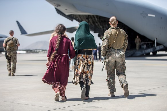 epa09427970 A handout photo made available by the US Marine Corps via DVIDS showing a Marine with the 24th Marine Expeditionary Unit (MEU) accompanying the children during an evacuation at Hamid Karzai…