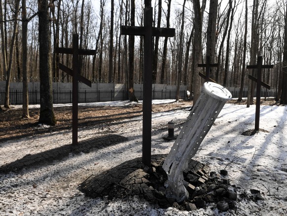 epa09844784 A Russian cluster bomb is seen next to a cross at the War Cemetery Kharkiv-Pyatikhatki in Kharkiv, Ukraine, 23 March 2022. Russian troops entered Ukraine on 24 February resulting in fighti ...
