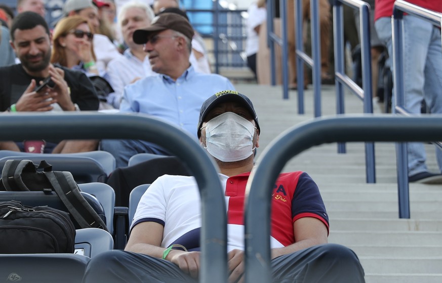 FILE - In this Friday, Feb. 28, 2020, file photo, a tennis fan wearing a facemask waits for the start of the semifinal matches of the Dubai Duty Free Tennis Championship in Dubai, United Arab Emirates ...