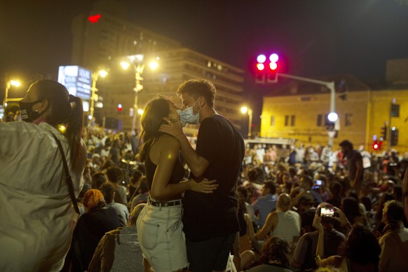 A couple kisses while wearing face masks to curb the spread of the coronavirus during a protest against Israel&#039;s Prime Minister Benjamin Netanyahu outside his residence in Jerusalem, Tuesday, Aug ...