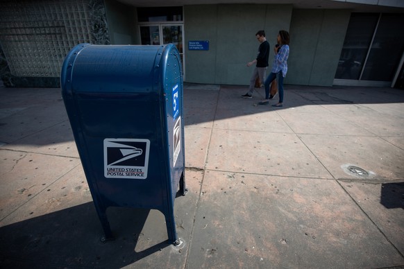 epa08608317 People walk past a USPS mailbox in Los Angeles, California, USA, 16 August 2020. According to media reports, House Speaker Nancy Pelosi announced she was calling the House of Representativ ...