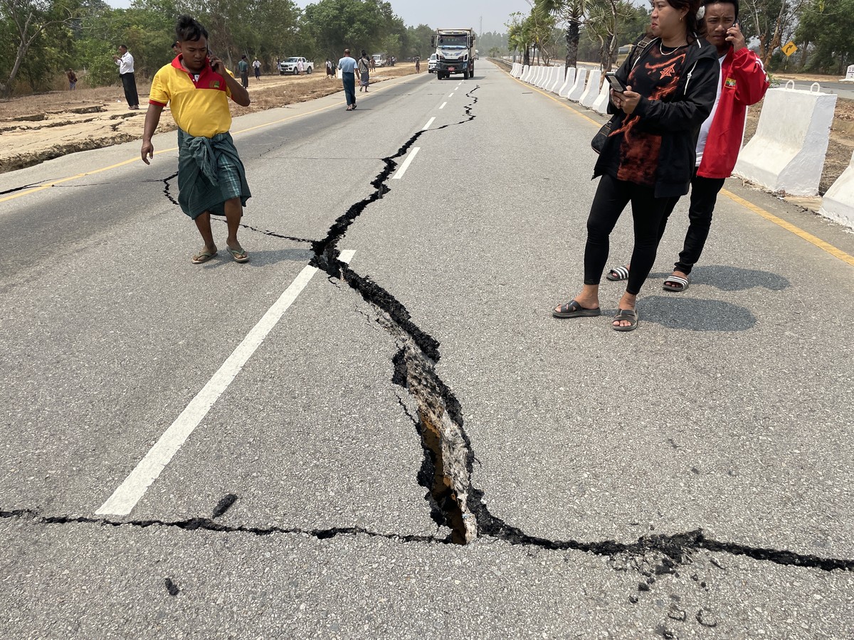 epa11993938 People look at a damaged road on the Naypyidaw-Yangon highway after an earthquake, in Naypyidaw, Myanmar, 28 March 2025. A 7.7-magnitude earthquake struck Myanmar, according to the United  ...