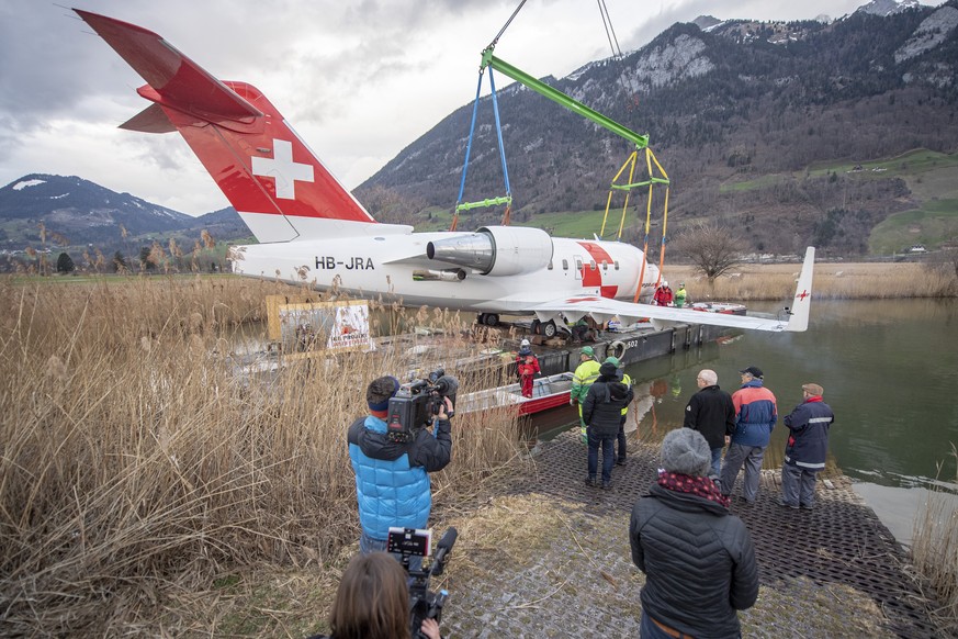 Der Rega Ambulanzjet CL-604, HB-JRA wird am Freitag, 8. Maerz 2019 auf ein Ponton hehievt, dies anlaesslich des Transports vom Flugplatz Alpnach ber den Vierwaldstaettersee nach Luzern ins Verkehrsha ...